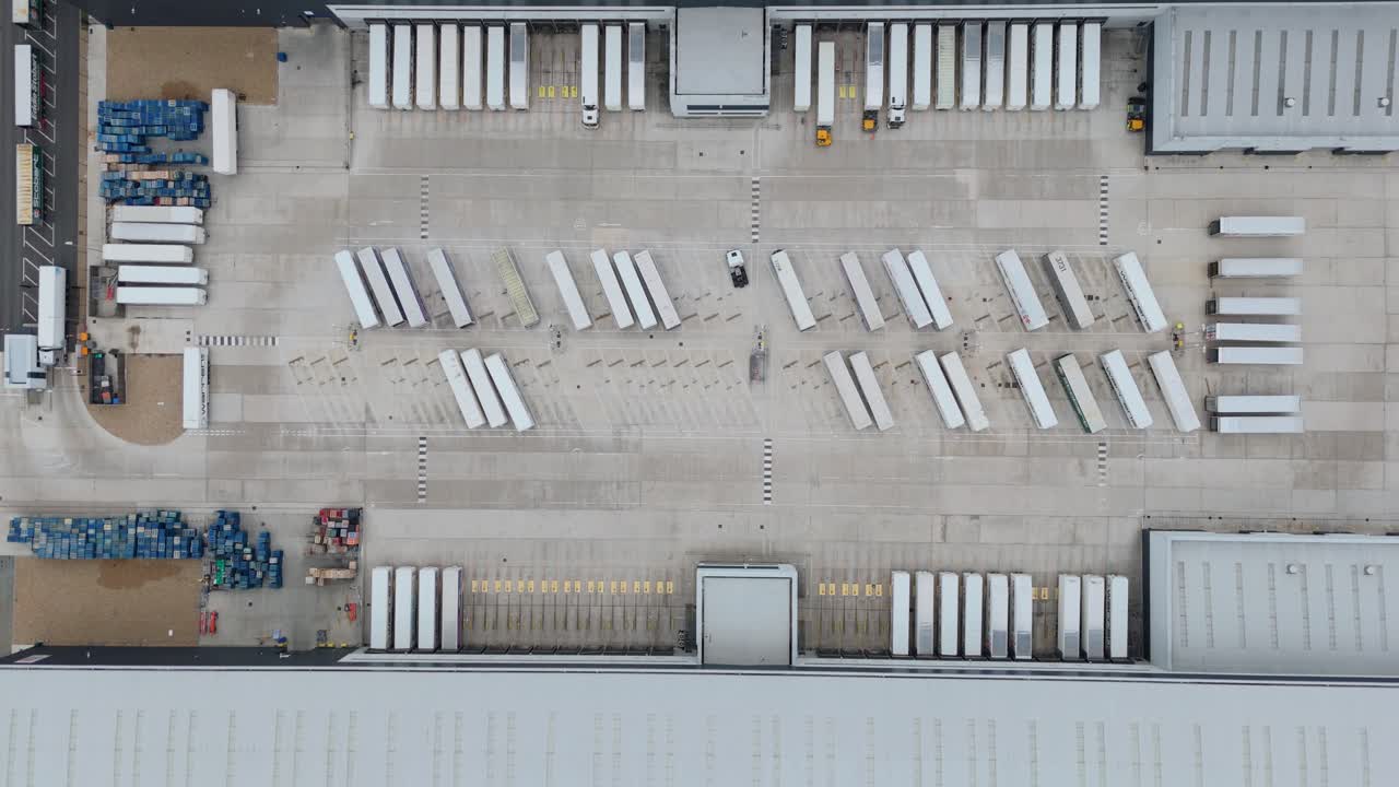 Cinematic drone top down aerial overhead footage of huge warehouse logistics park with trailers, trucks and distribution hub near Lutterworth England United Kingdom