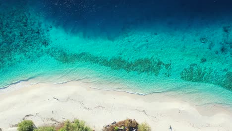 Colorful-shoreline-of-tropical-island-with-blue-azure-sea-washing-white-sand-of-exotic-unspoiled-beach-in-Turks-and-Caicos