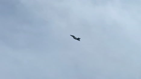 a jet aircraft performs maneuvers beneath a cloudy, overcast sky, showcasing dynamic aerial movement.