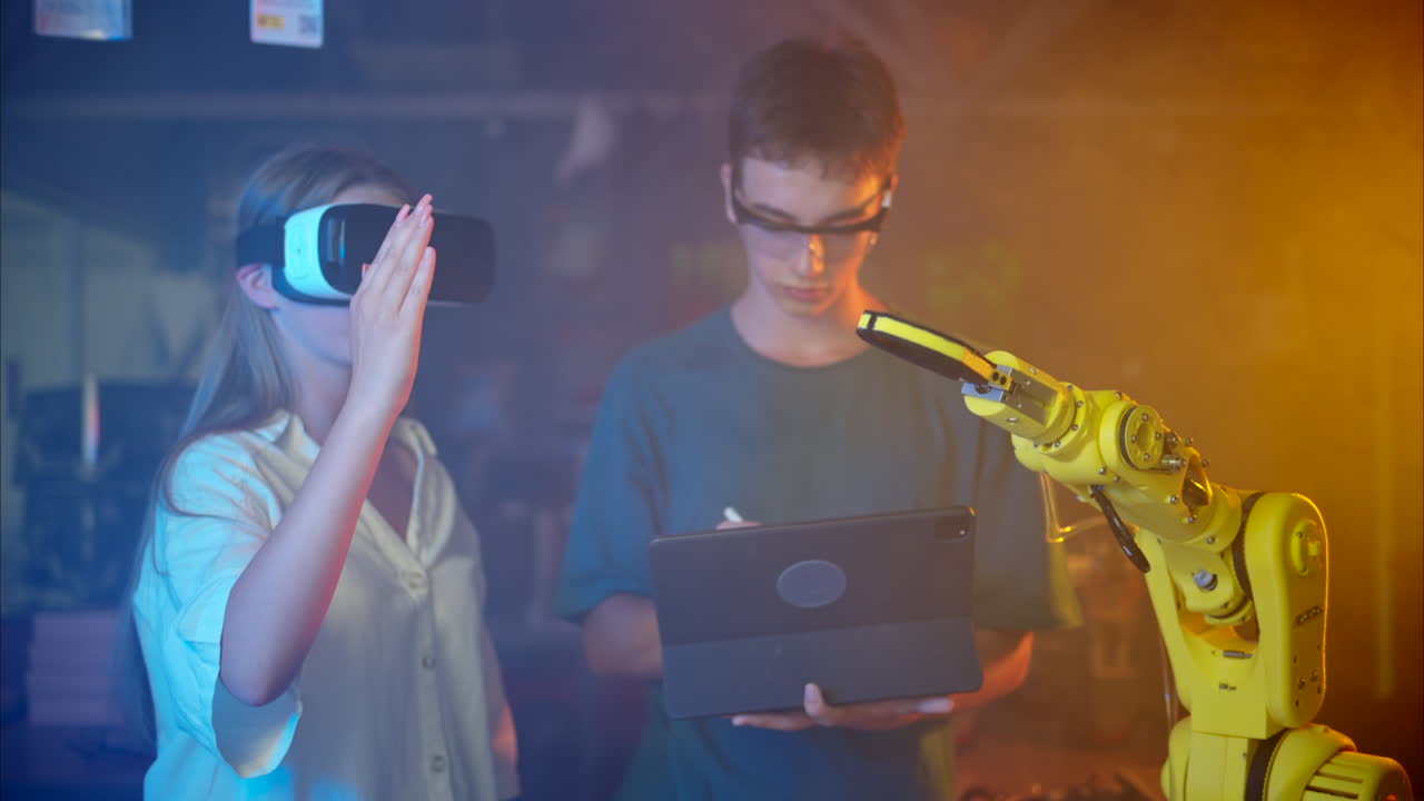 Young engineers with VR virtual reality headset controlling an yellow robotic arm in research laboratory