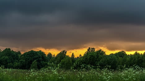 landscape time-lapse of storm clouds over a countryside field at sunset