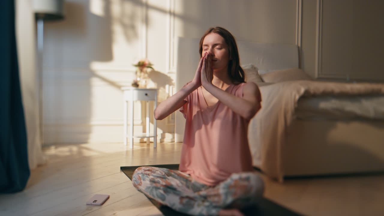 chica de la mañana haciendo yoga en la luz del sol en casa. mujer tranquila y relajada en posición de loto