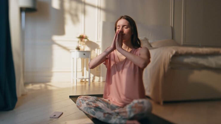 Ragazza che fa yoga al mattino a casa, alla luce del sole. Donna calma e rilassata in posizione del loto.