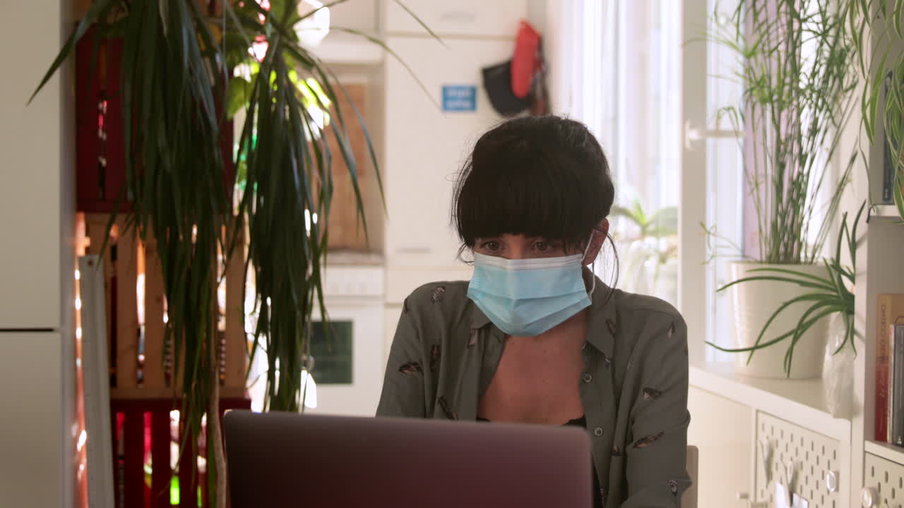 Brunette woman video calling through computer with mask