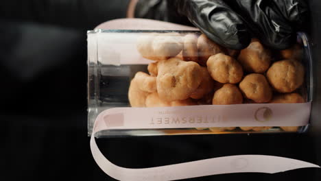 person in gloves handling a jar of bittersweet cookies