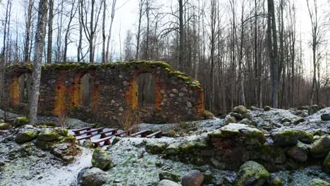 la pared de roca de la iglesia abandonada permanece con nuevos asientos en el bosque de árboles desnudos