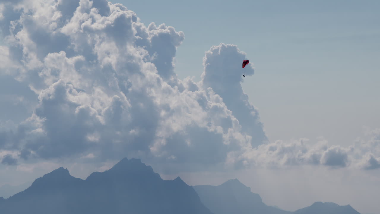 패러글라이더가 산과 구름 위를 날고 있다