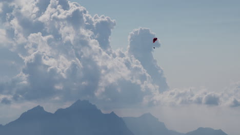 a paraglider is flying above mountains and clouds