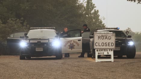 police cars, lights flashing, block road as officers stand by, creek fire, california
