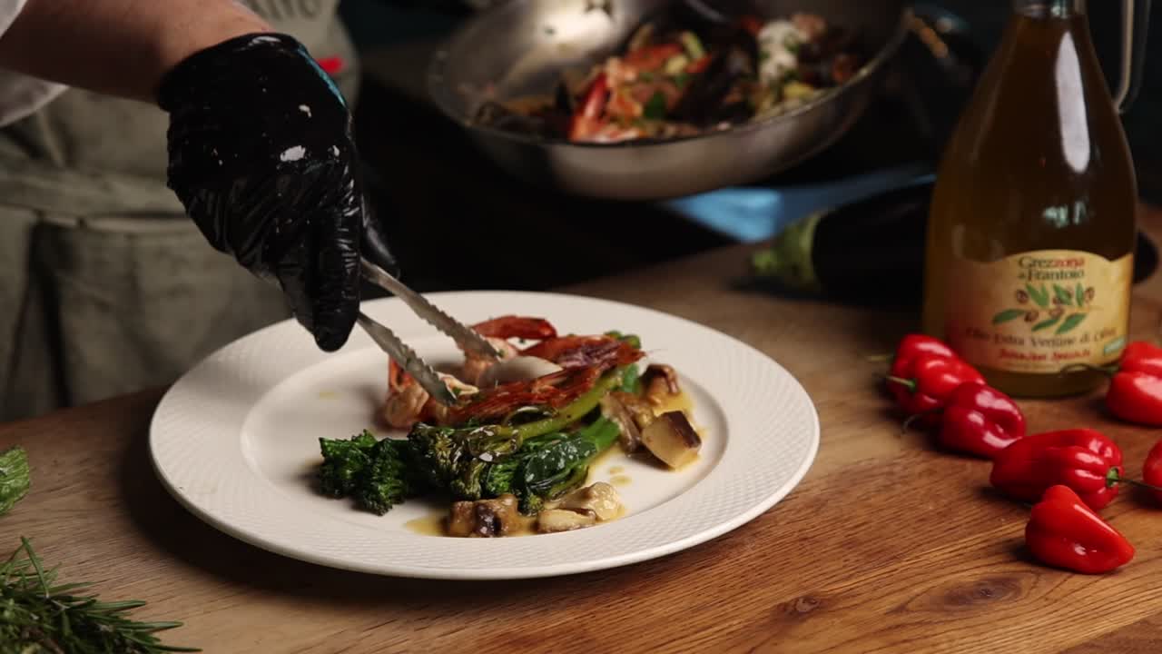 Chef emplatando un plato gourmet de camarones y verduras en una cocina de restaurante