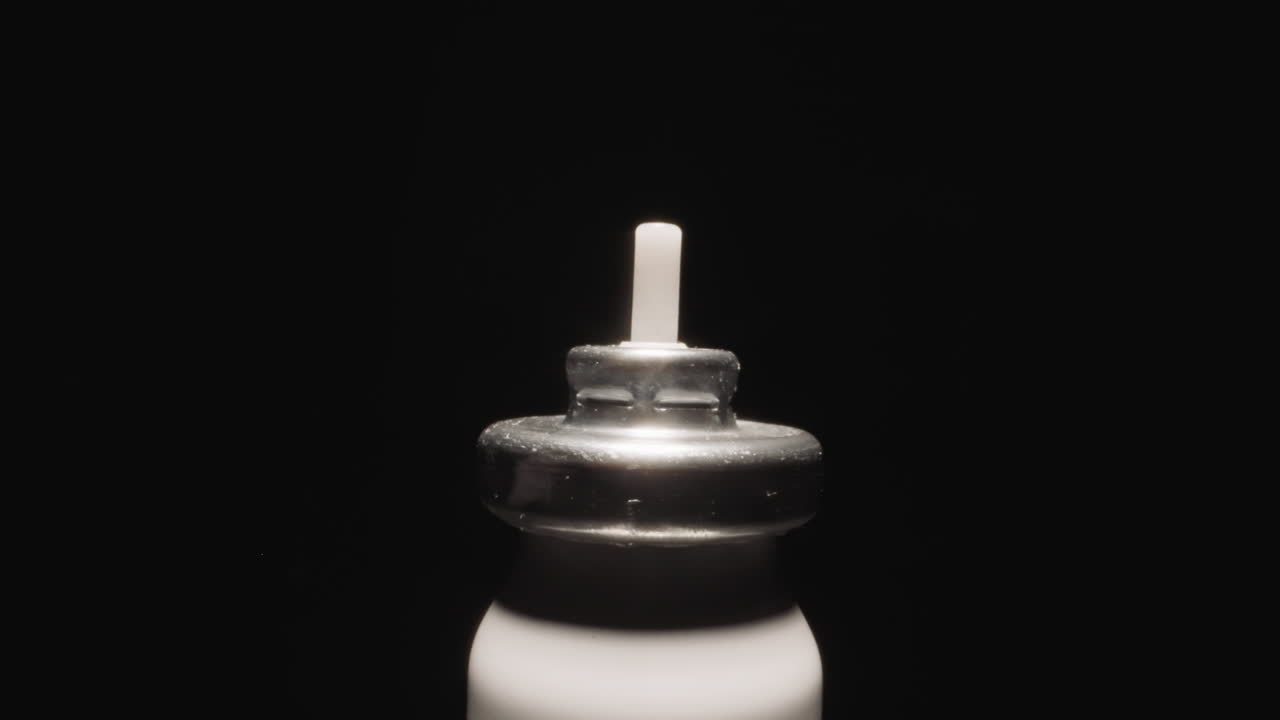 Bottle from inhaler with metal cap shining at studio light