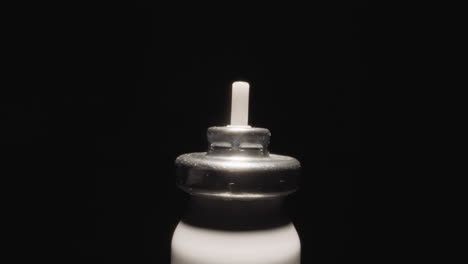 Bottle-from-inhaler-with-metal-cap-shining-at-studio-light