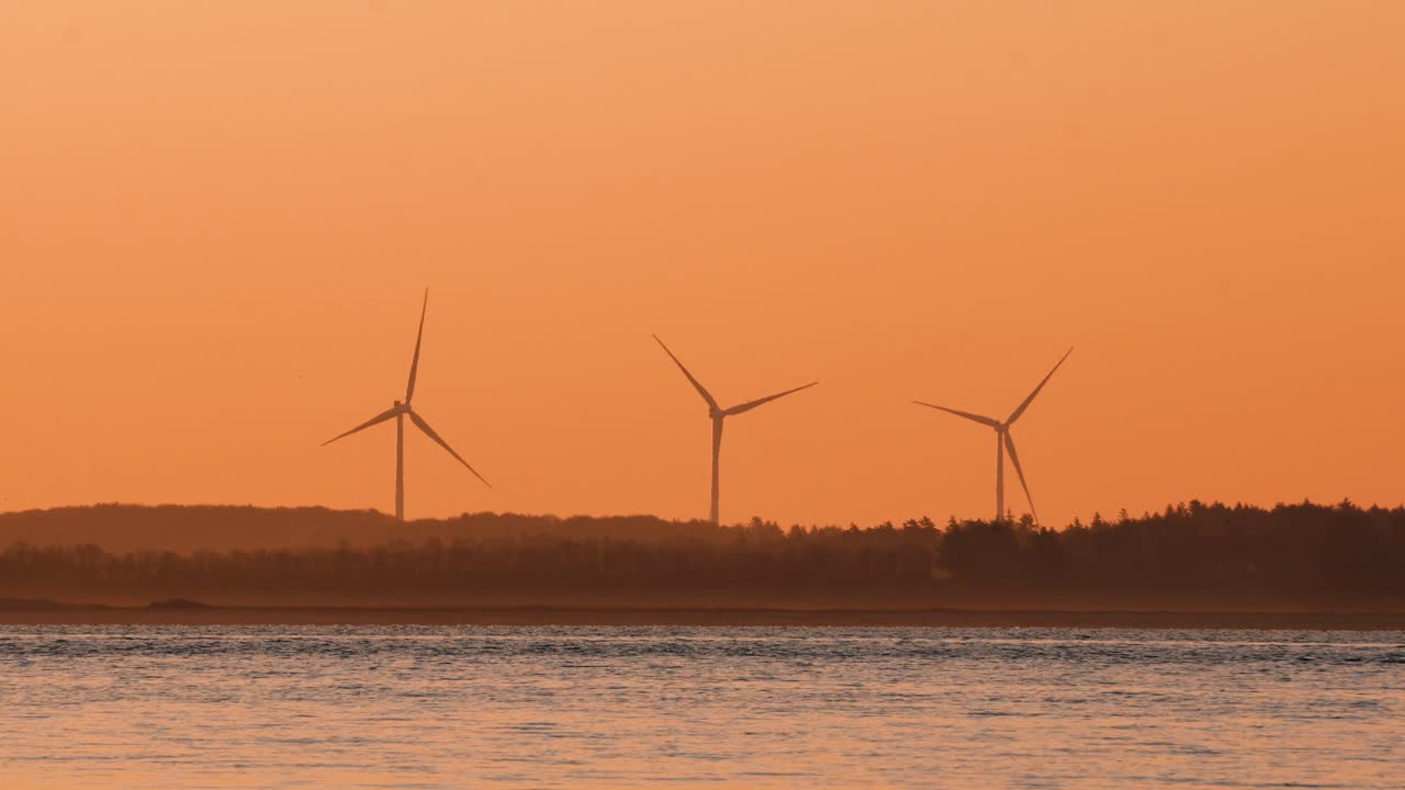 전경에 바다가 있는 육지의 풍차 발전
