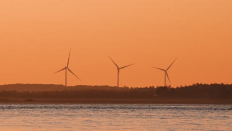 Powergenerating-windmills-on-land,-with-sea-in-the-foreground