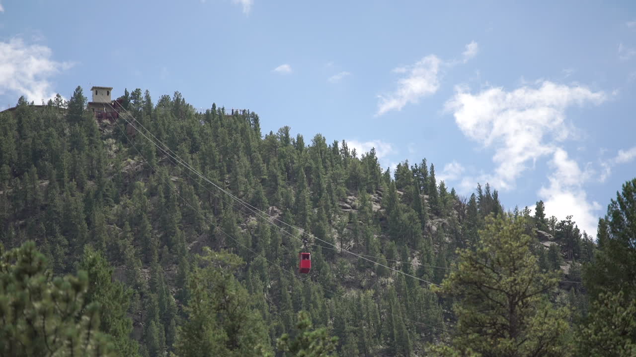 Gondola rossa che passa accanto a una funivia che sale la montagna.
