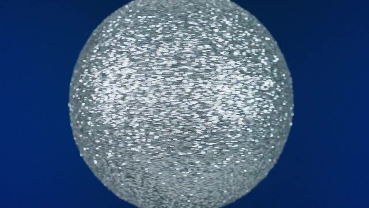 Palla glitterata argentata che ruota contro uno sfondo blu intenso.