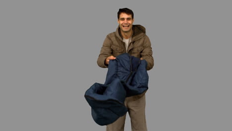 cheerful man rolling out his sleeping bag on grey screen