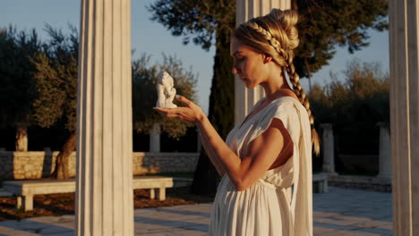 woman in ancient greek dress holding a statue