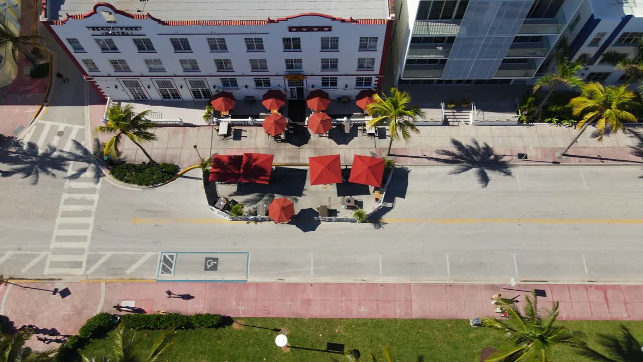 de arriba hacia abajo drone disparó panorámica de la calle de la playa, cuenta con coloridas tiendas de campaña, restaurantes, personas, bicicletas, palmeras y edificios