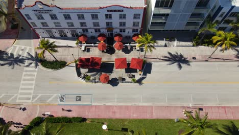 de arriba hacia abajo drone disparó panorámica de la calle de la playa, cuenta con coloridas tiendas de campaña, restaurantes, personas, bicicletas, palmeras y edificios