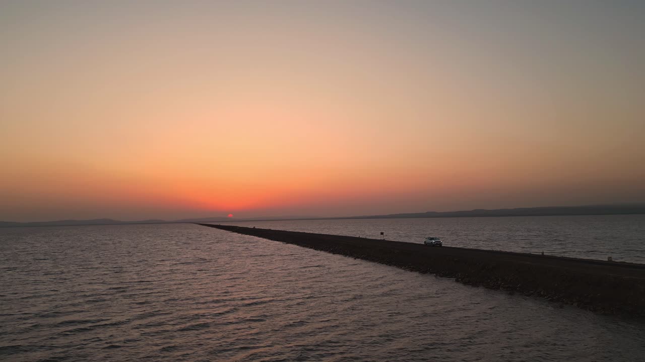 A stunning top drone view of a truck driving on the Road to Heaven in Kutch, Gujrat a breathtaking highway flanked by the sea on both sides. The golden sunset casts a mesmerizing glow