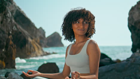 african girl meditating lotus position on rocky shore ursa beach close up