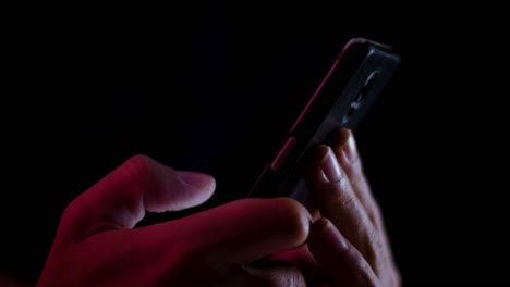 thumb scrolling up and down on a smartphone close up in a dark room with red and white lighting
