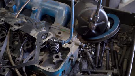 workbench with close up of engine cylinder head and miscellaneous auto parts