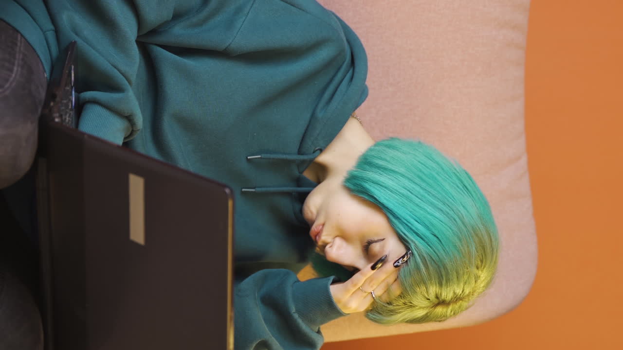 노트북에서 일하는 젊은 여성의 수직 비디오가 두통을  ⁇ 고 있습니다.