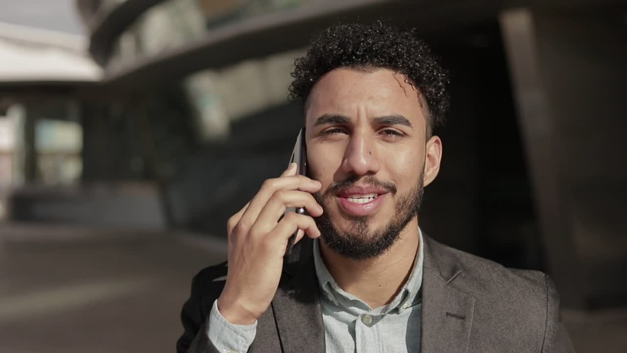 hombre alegre con cerdas hablando en el teléfono inteligente al aire libre