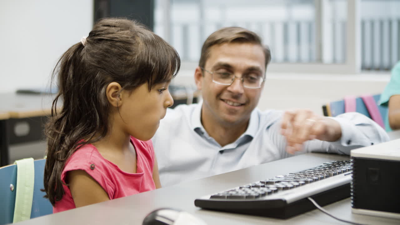 chica hispana escribiendo en el teclado de la computadora mientras un profesor la ayuda