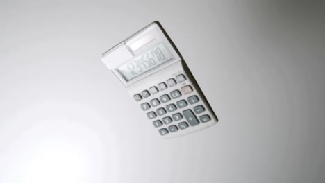 pocket calculator falling on white surface