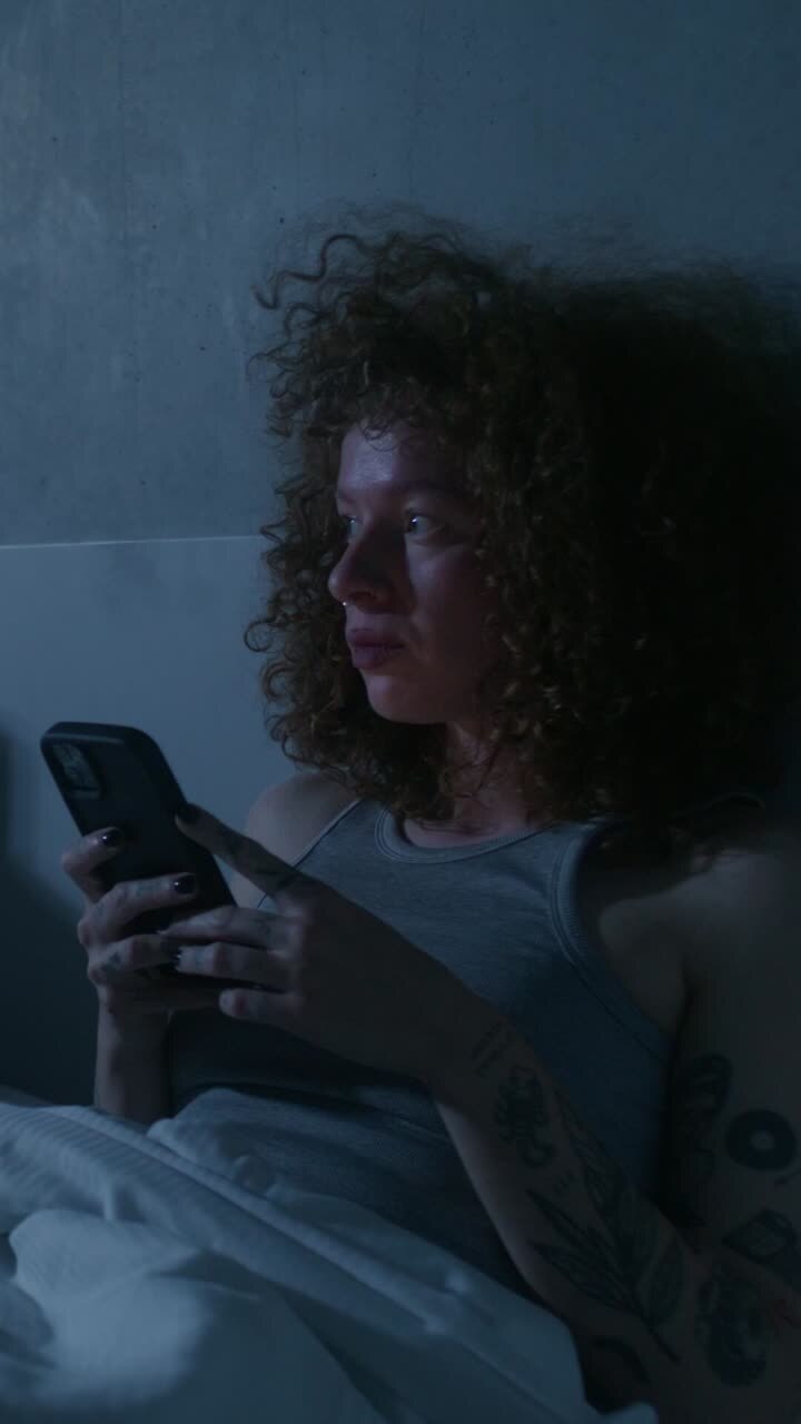 Woman using smartphone in bed at night