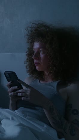 woman using smartphone in bed at night