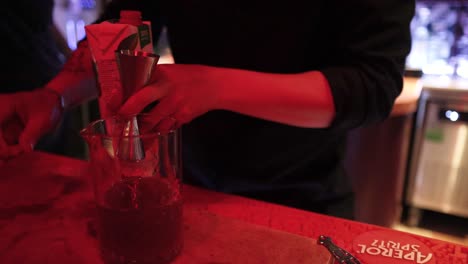 a bartender skillfully mixes a cocktail in a dimly lit bar, using precise techniques and vibrant ingredients