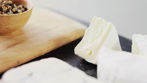 sliced cheese, bowls of jam and spices on wooden board