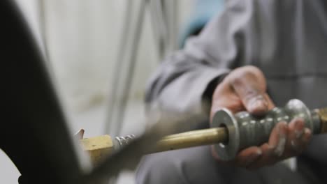 african american male car mechanic holding a screwdriver and using a hammer to repair a car