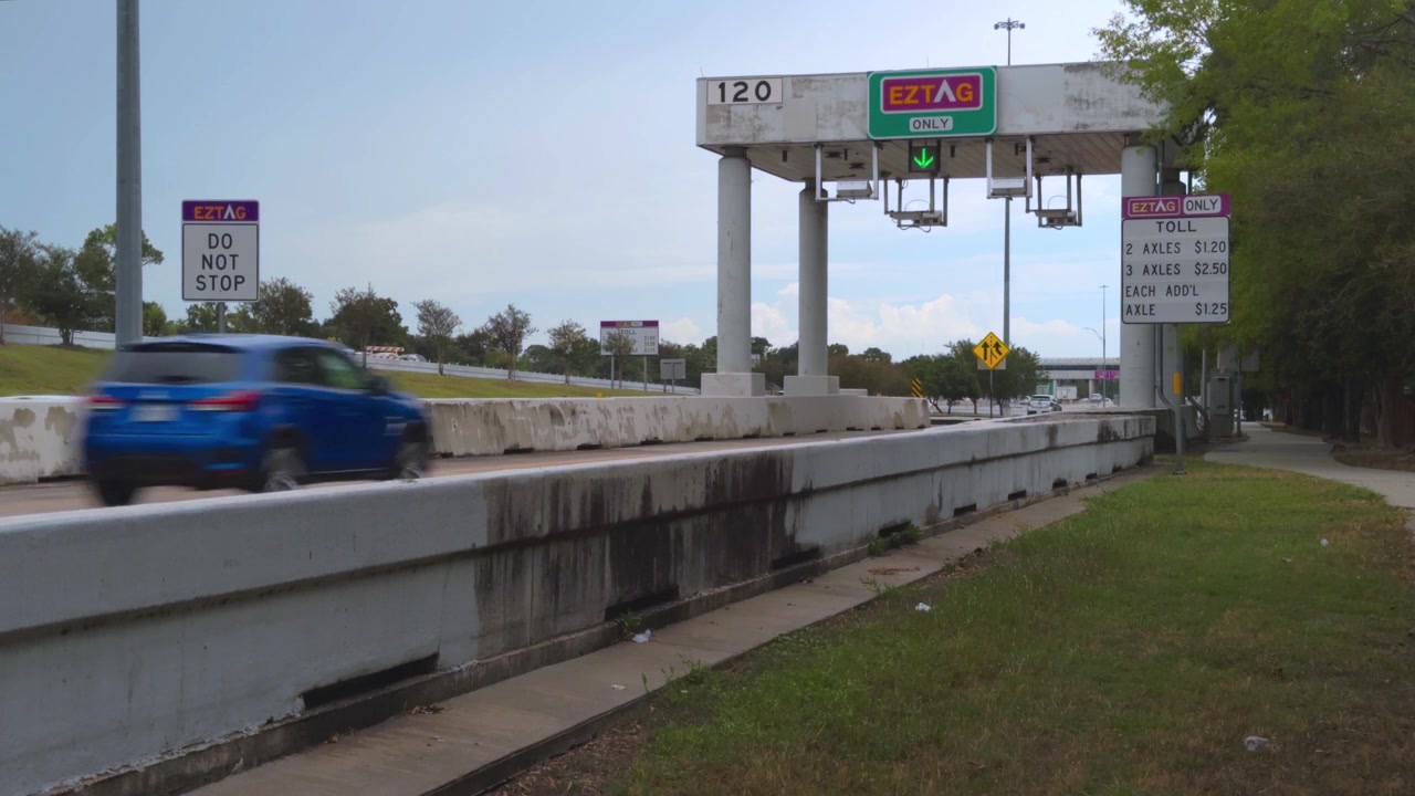 Inquadratura d'apertura che mostra l'ingresso del casello sulla Beltway 8 (Sam Houston Tollway) a Houston, Texas, uno dei principali corridoi di trasporto della regione gestito dalla Harris County Toll Road.