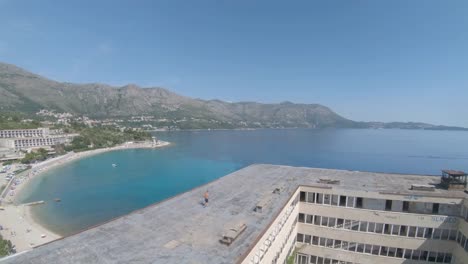 aerial drone footage of man running across the rooftop of an abandon hotels on kupari beach, croatia