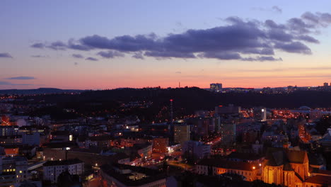 zoom inside square city street in brno during sunset covered by cars ride through mendlovo square with orange clouds on sky and city light which goes on line landscape view captured in 4k 60fps