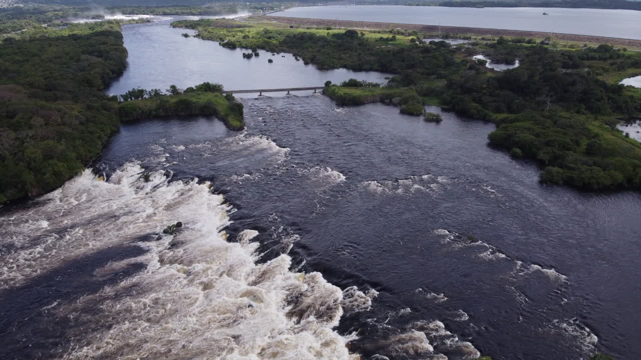 Aerial view of a river with rapids flowing towards a dam and reservoir
