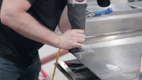 man's hands using reciprocating saw at workshop to cut metal plate