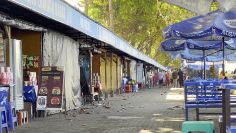 people strolling past food stalls at a lively lombok barat street market