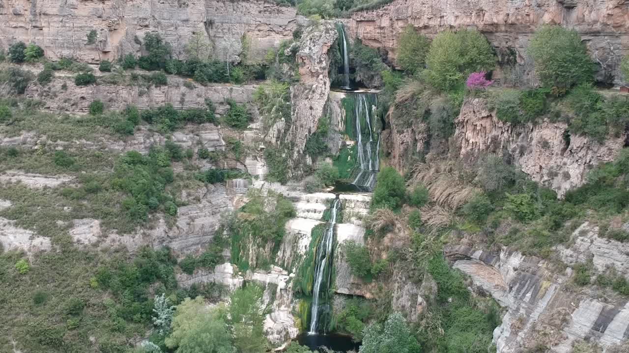 Vedute aeree di una cascata con una grotta e un vecchio edificio in Catalogna, Spagna