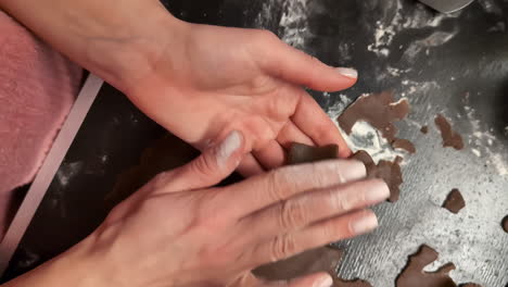 closeup of hands delicately peeling cute cookie shapes out of homemade cookie dough using stencil cutter