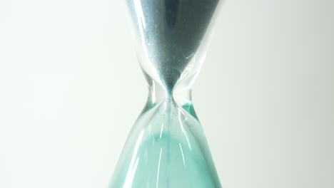 slow motion footage of green sand falling through the centre of an hour glass in close up