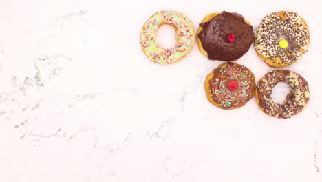 las rosquillas dulces con chocolate blanco y negro aparecen y desaparecen de la mesa de mármol - detenga el movimiento