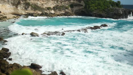 Mid-slow-motion-shot-of-waves-breaking-over-rocks-at-blue-lagoon-in-Nusa-Lembongan,-Indonesia