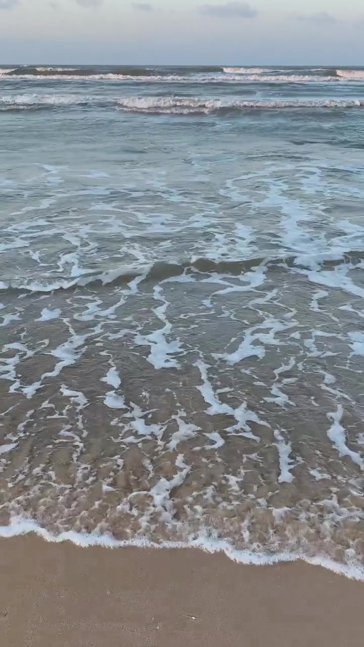 Dolci Onde dell'Oceano che si Infrangono su una Spiaggia Sabbiosa al Tramonto