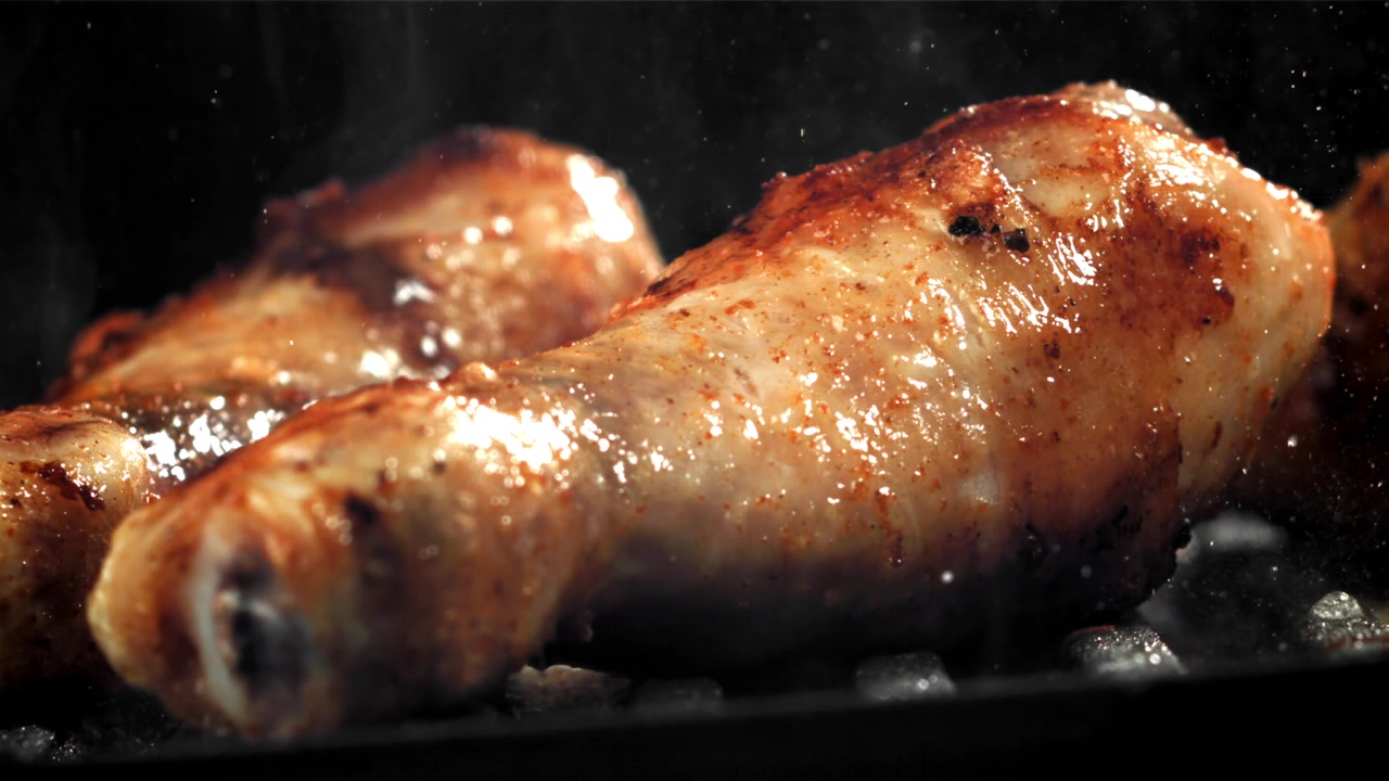 Deliziosi fusi di pollo che cuociono su una griglia calda